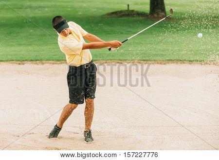 Golfer Playing From Sand Trap. Ball and grains of sand frozen in the air