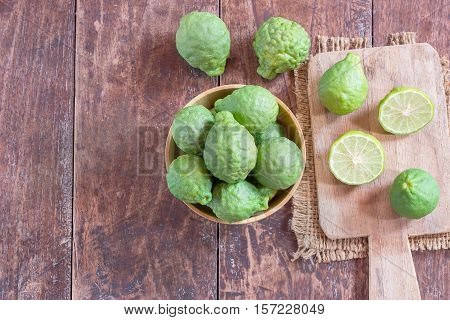 Close up fresh bergamot and bergamot slice in wooden bowl on dark wood table background. bergamot on old wooden brown with copy space. (Bergamot or Kaffir lime)