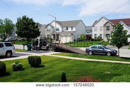 JOLIET, ILLINOIS / UNITED STATES - MAY 24, 2016: A tow truck prepares to remove a disabled vehicle in the Wesmere Country Club subdivision of Joliet.