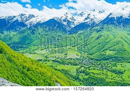 The view from the mountain on deep gorge with villages fields and pastures surrounded by sbowy peaks of Caucasus Upper Svaneti Georgia.