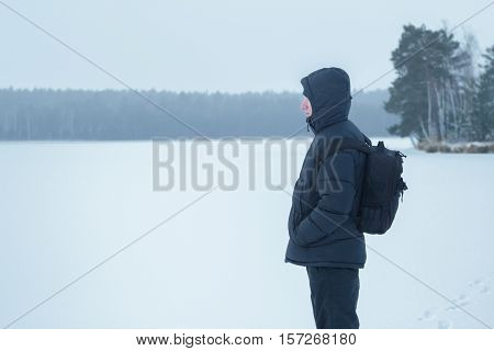 Winter hiking sportsman is looking at snowy plain wood amazing landscape