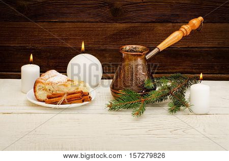 Pots of coffee fir twig apple pie cinnamon sticks and candles on the wooden background