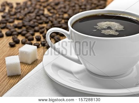 Coffee cup on a table, coffee beans and lump sugar around, studio shot