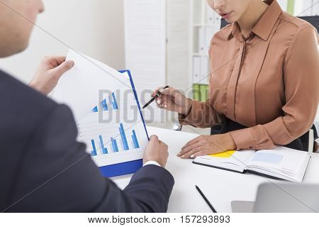 Close Up Of Two Office Employees Working With A Diagram