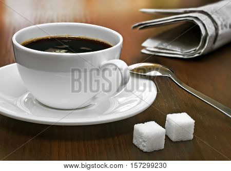 Coffee cup lump sugar (sugar cubes) and newspapers on a table