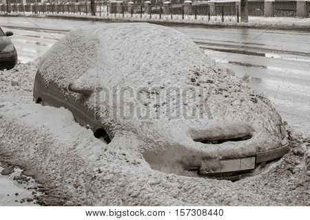 Car on winter road covered with snow. Vehicle on snowy alley in the morning after snowfall in city. A street with cars are covered with snow in wintertime.