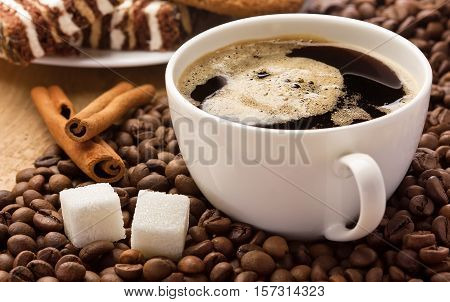 Coffee cup cinnamon and sugar cubes on coffee beans sweets on the background