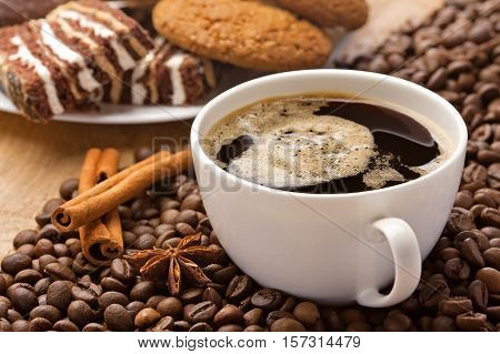 Coffee cup cinnamon anise on coffee beans sweets on the background