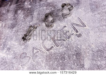 Baking (Backen) in German letters written in flour on the table