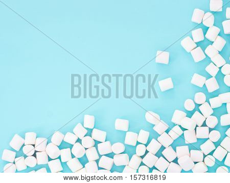 Marshmallows on blue background with copyspace. Flat lay or top view. Background or texture of colorful mini marshmallows.