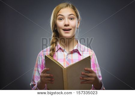 wondering girl with book. Closeup Portrait of handsome teen in casual shirt on grey background. studies concept.