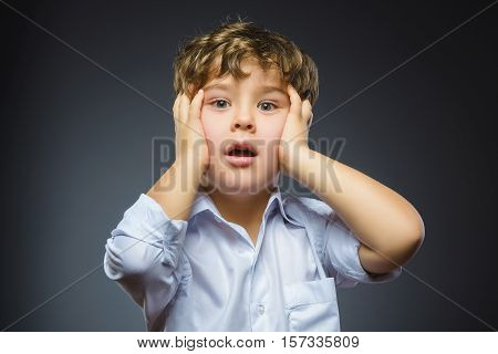 Closeup Portrait of handsome boy with astonished expression while standing against grey background.