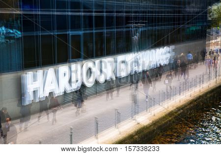 Multiple exposure effect image. Office workers walking against of Harbour Exchange sign