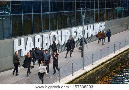 LONDON, UK - November 16, 2016: Canary Wharf. Office workers walking against of Harbour Exchange sign