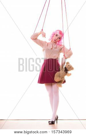 Mental disorder concept. Young woman girl stylized like marionette puppet on string with teddy bear toy isolated on white background