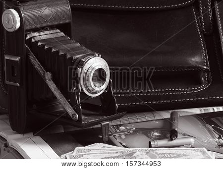 Vintage camera, briefcase, pen and money over vintage car magazine all from fifthies
