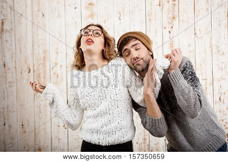 Young handsome man unnerve his girlfriend holding phone over wooden background.