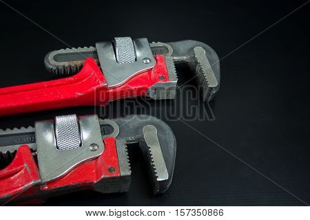 Red pipe wrench on black background construction concept.