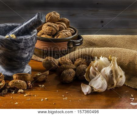 Mortar and pestle with fresh herbs greek nuts garlic on wooden table
