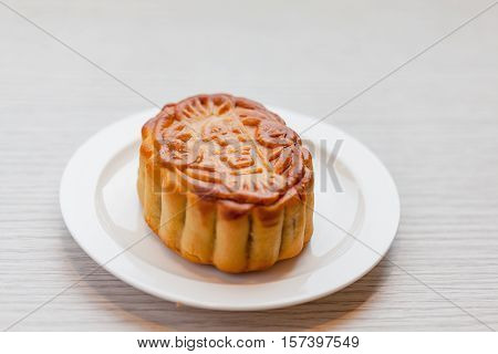 Chiness moon cake with white plate on the wooden table / 2 Chiness capital letters are wish and not trade mark.