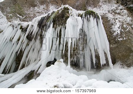 Frozen beautiful waterfall in winter. Icicles and mountain river.