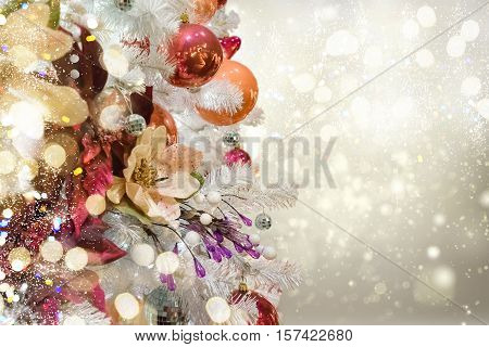 christmas white tree with holiday red and orange decorations and lights with copy space on silver bokeh background