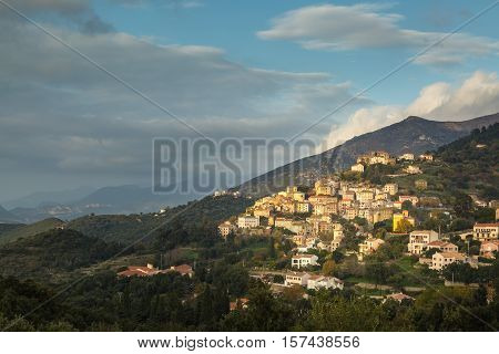Afternoon sun shining on the colourful houses of the village of Oletta on a hillside in the Nebbio region of northern Corsica