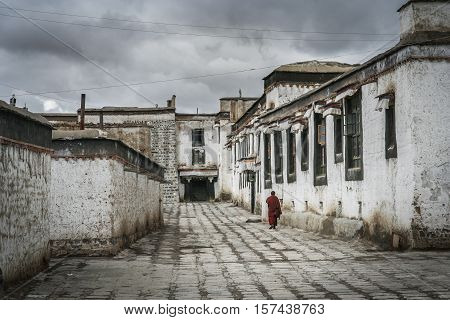 Monk walking in the courtyard between buildings in the compound of the Tibetan Monastery in Shigatse in central Tibet