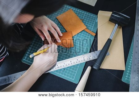 Women working with leather using crafting tools.