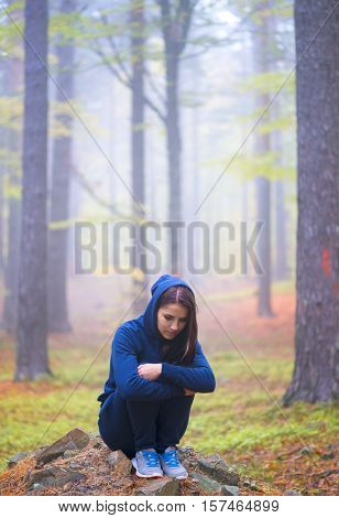 Depressed woman standing alone in forest in autumn