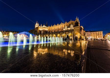 KRAKOW POLAND - 15TH OCTOBER 2016: The Cloth Hall on Rynek Glowny (Main Square) in Krakow at night with the Fontanna na Rynku Głownym. The blur of people can be seen.