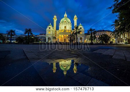 VIENNA AUSTRIA - 3RD OCTOBER 2016: The outside of Karlskirche in Vienna at night. Reflections can be seen in the pond.
