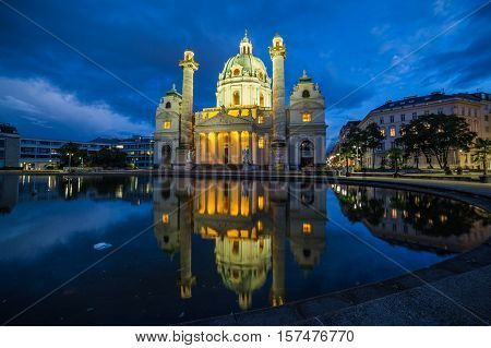 VIENNA AUSTRIA - 3RD OCTOBER 2016: The outside of Karlskirche in Vienna at night. Reflections can be seen in the pond.