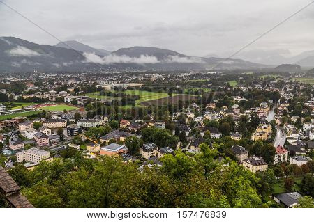 A high view of buildings in part of Salzburg Austria during the day. Low clouds can be seen.