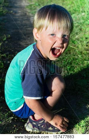little boy in shorts sitting on grass and smiling