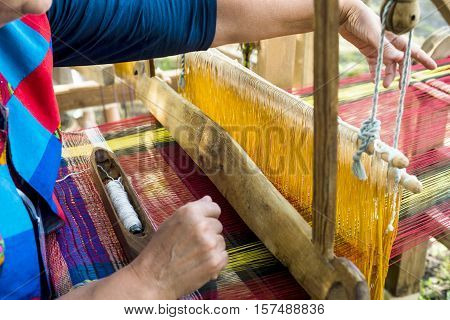 Weaving the threads on old wooden loom