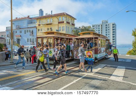 San Francisco, CA, USA - August 16, 2016: Two Cable Car of San Francisco, Powell-Hyde lines meet. Tourists crossing the intersection between Hyde and Lombard Street, popular touristic attraction.