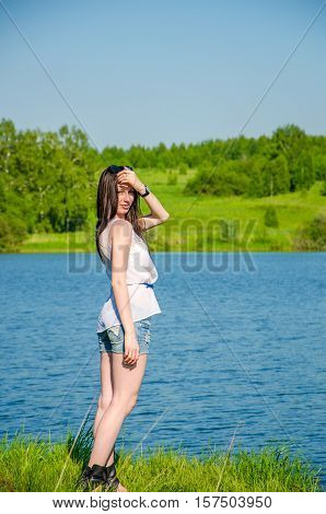 haired beautiful walks on the lake. girl in a summer forest near pond. Brunette standing near water. Girl in the forest near the pond.