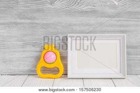 baby rattle and photo frame on wooden background top view