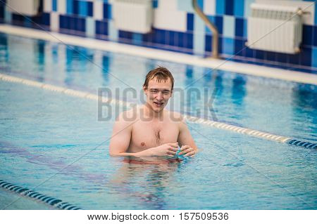 Young happy man in the swimming pool gesturing thumb up.