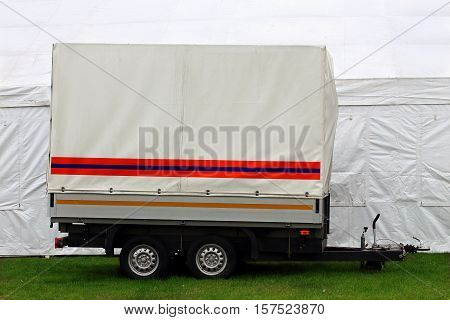 Two-axle trailer with white tent on  green grass