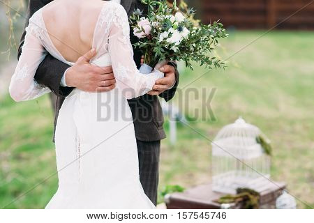 Just married couple dancing valse outdoor, free space. Bride and groom hugs, blurred green grass background. First wedding dance concept