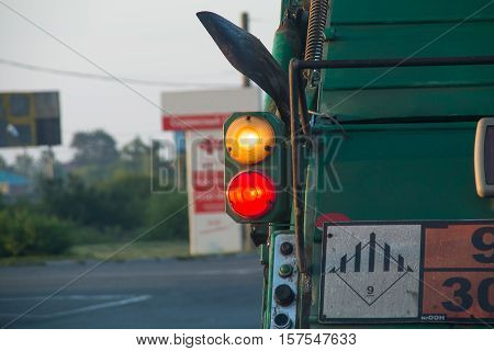 Rear view on a round taillight of the truck. Green garbage truck.
