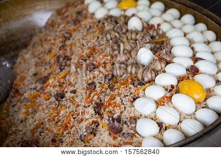 Traditional Asian pilaf with beef and chicken eggs. A large cauldron, rice devzira, cumin spices, cotton seed oil. The famous dish of the East