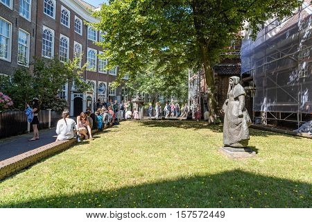 Amsterdam Netherlands - August 1 2016: Crowd in the Begijnhof. It is one of the oldest inner courts in the city of Amsterdam. A group of historic buildings centre on it.