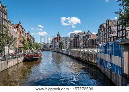 Amsterdam Netherlands - August 1 2016: Canal with a touristic boats near flower market. Amsterdam is the capital and most populous city of the Netherlands and one of the top financial centres in Europe
