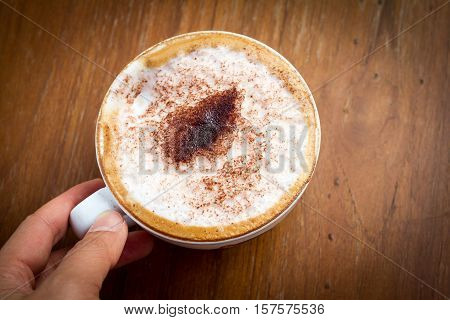 Cup of cappuccino coffee on wood background