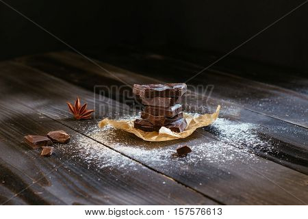 Chocolate on the black wooden table. Dark chocolate. Chocolate chunks