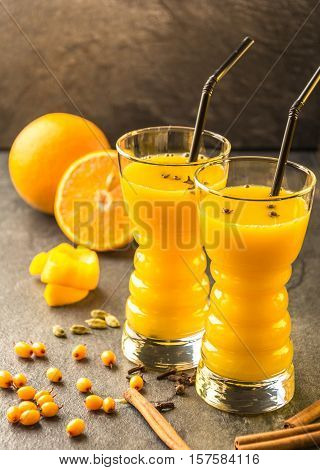 orange sea buckthorn juice with orange, sea buckthorn , cinnamon, carnation and cardamon on a dark table