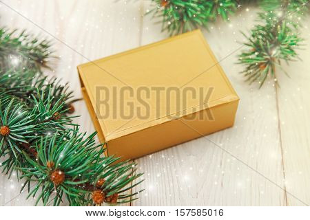 Christmas composition.Tree branch framegolden present box.White wooden table.Mokup with free space.